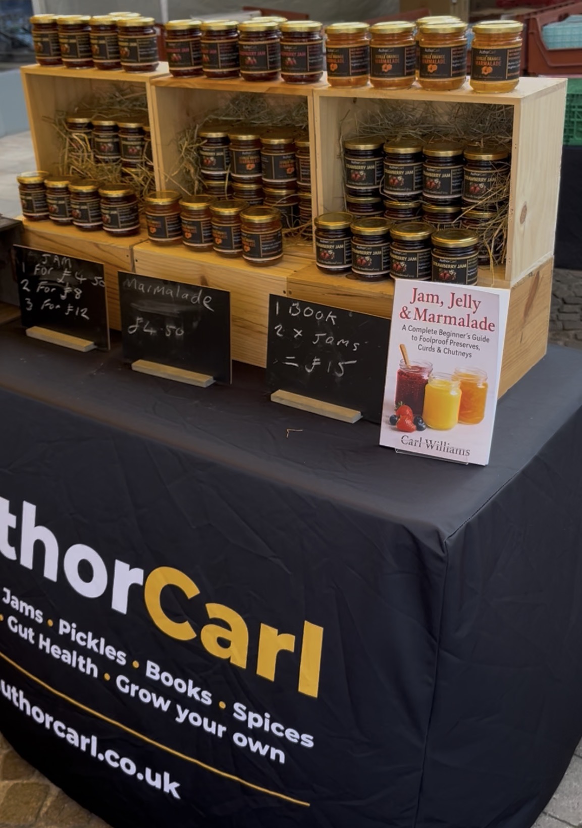 Author Carl market stall display with homemade food products and books